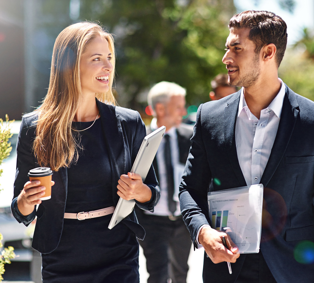 Versicherungslösungen für Unternehmen Zwei berufstätige Personen gehen gemeinsam durch einen Geschäftsbezirk. Das Bild steht für professionelle Risikoanalysen und massgeschneiderte Versicherungslösungen für Unternehmen.
